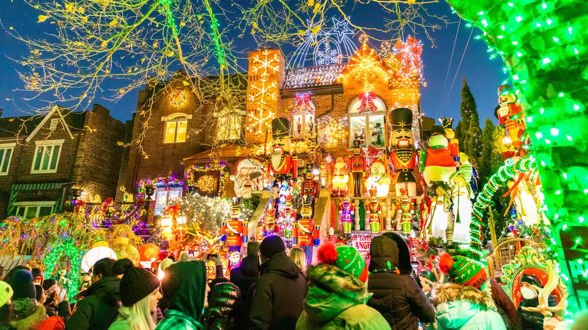 A Dyker Heights house covered in colored lights, with life-size nutcrackers and Christmas figures on the front steps