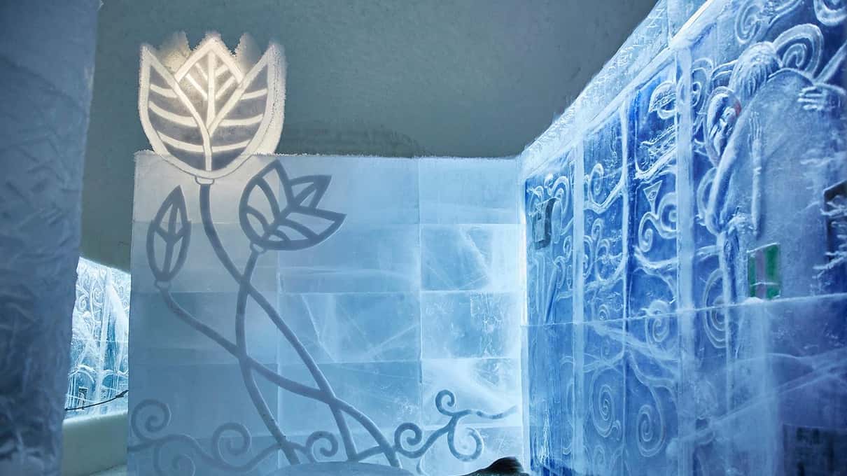 An Icehotel art suite with a tall carved flower and swirling patterns cut into the ice walls