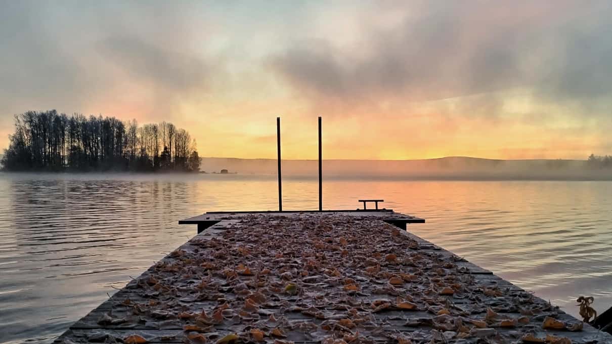 A frosty wooden jetty with a swim ladder running into the Kemijoki under a pink sunrise