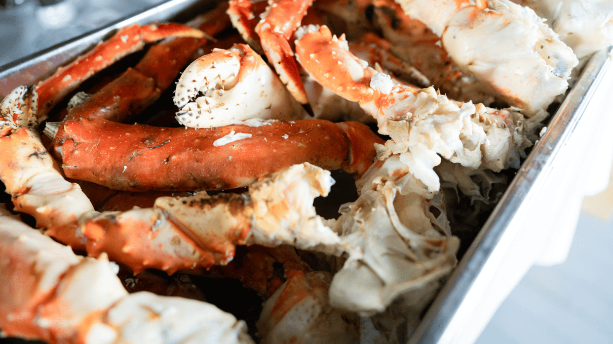 A steel tray piled with cooked red king crab legs and claws ready to be cracked