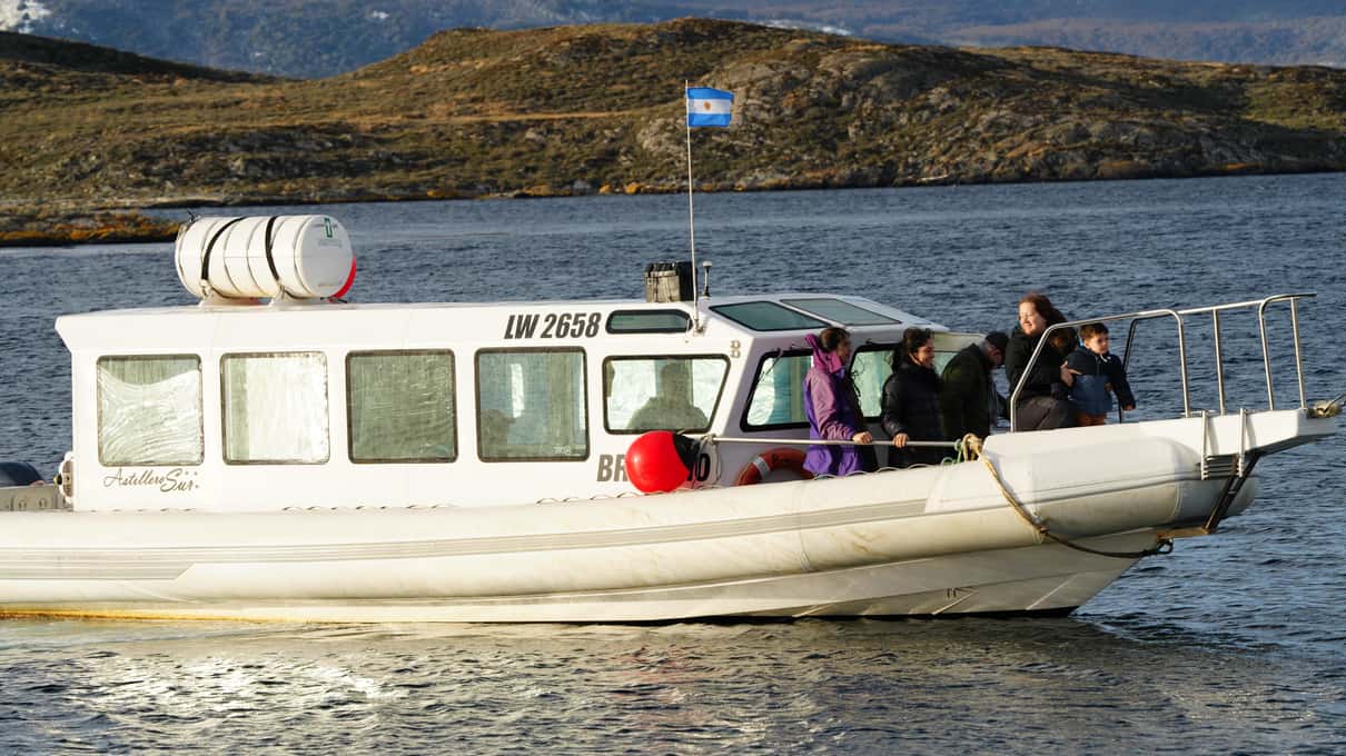 A small white cabin boat with a handful of passengers out on the Beagle Channel
