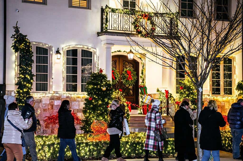 Brick house in Dyker Heights hung with wreaths and string lights, visitors on the pavement in front