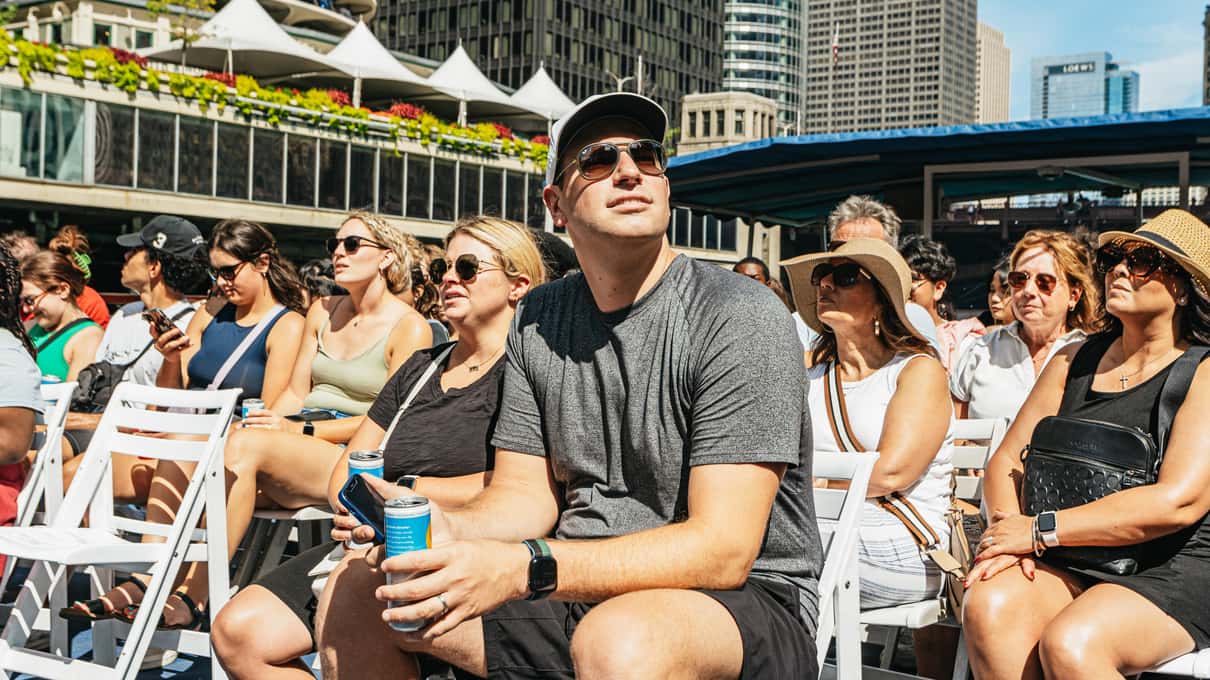 Smiling guests in sunglasses sitting on the open top deck of a Chicago river cruise boat