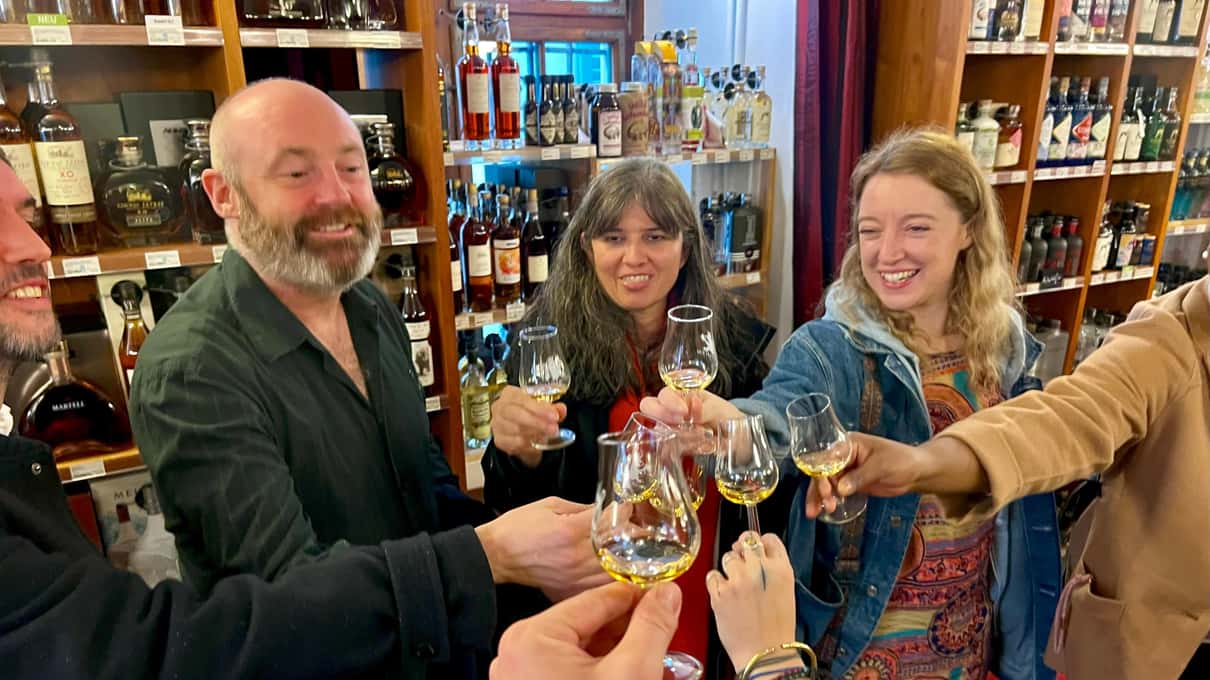 A small food tour group raising little glasses of schnapps among the shelves of a Zurich spirits shop
