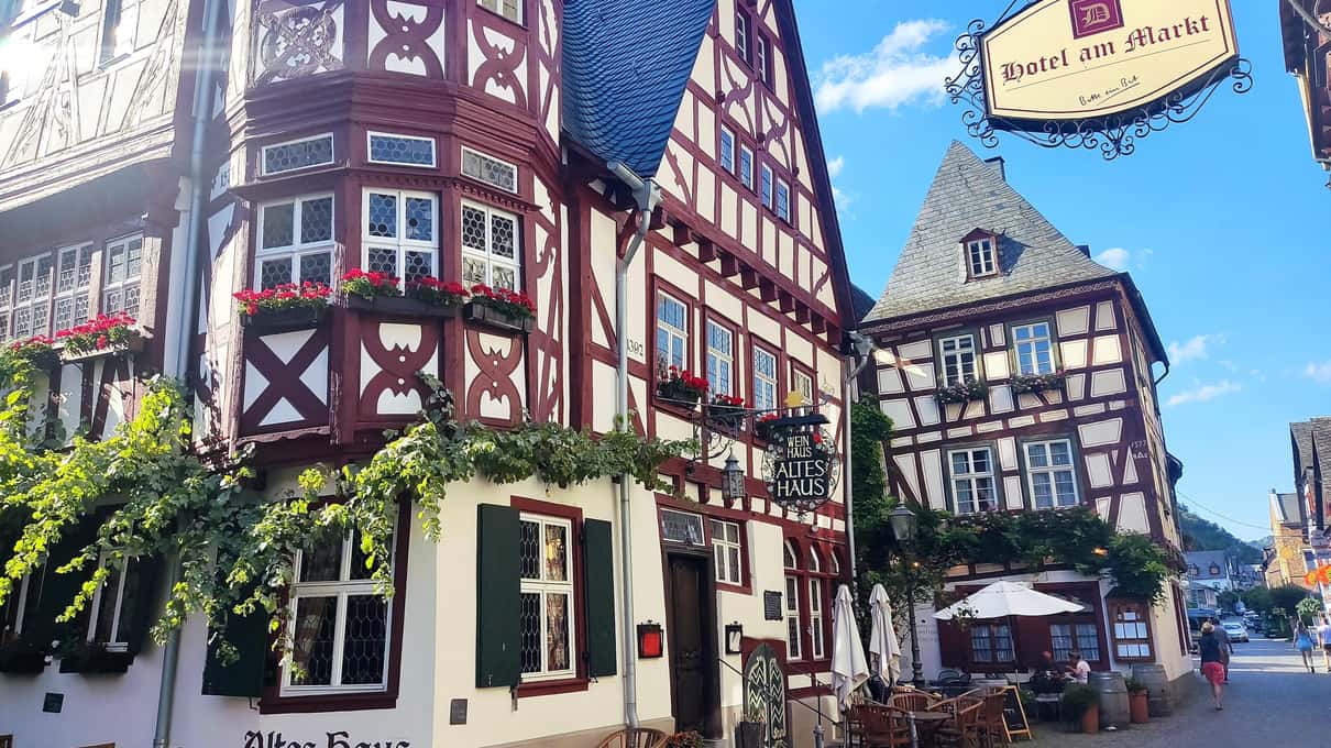 Colorful half-timbered houses with carved beams and a hanging wine-tavern sign in a Rhine town