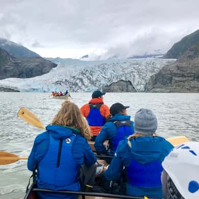 Blick von hinten auf Paddler im Kanu mit Gletscher im Hintergrund