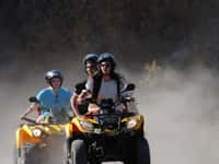 Three riders on quads in dust