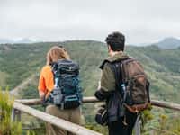 Two hikers at viewpoint over green hills