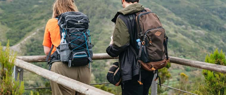 Two hikers at viewpoint over green hills