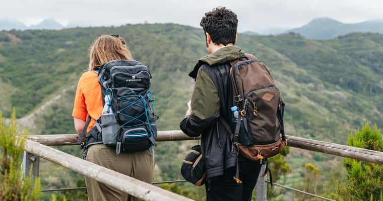 Two hikers at viewpoint over green hills