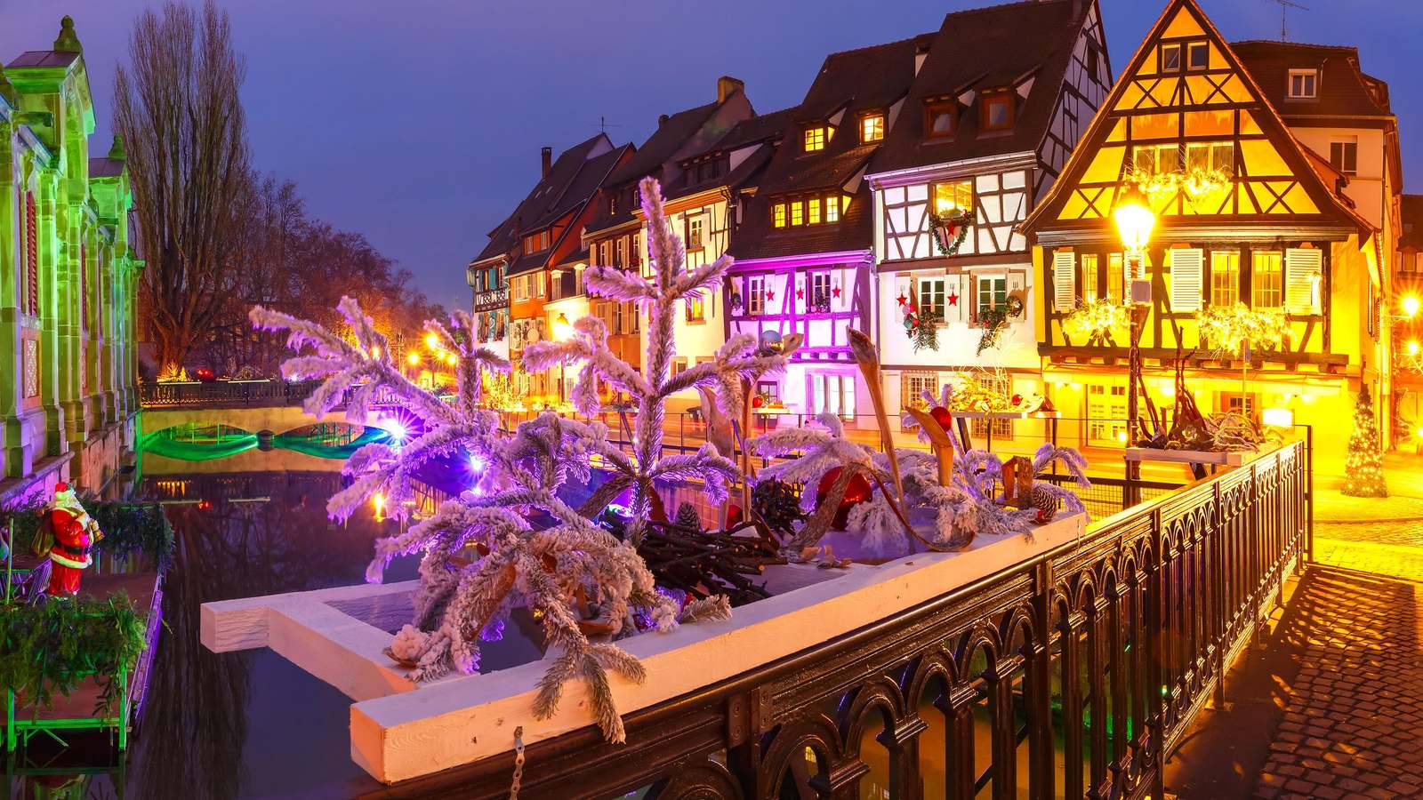 Colmar canal lined with half-timbered houses and a lit Christmas tree at night