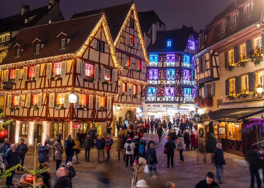 Evening crowd among lit half-timbered houses in Colmar old town during the Christmas market
