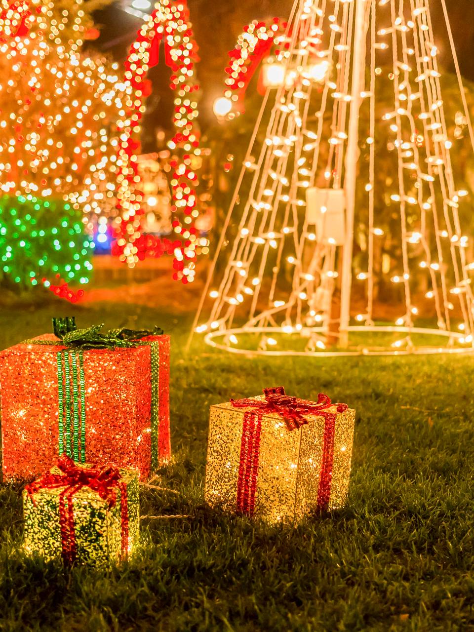 Gift boxes and a light-wrapped tree on a lawn