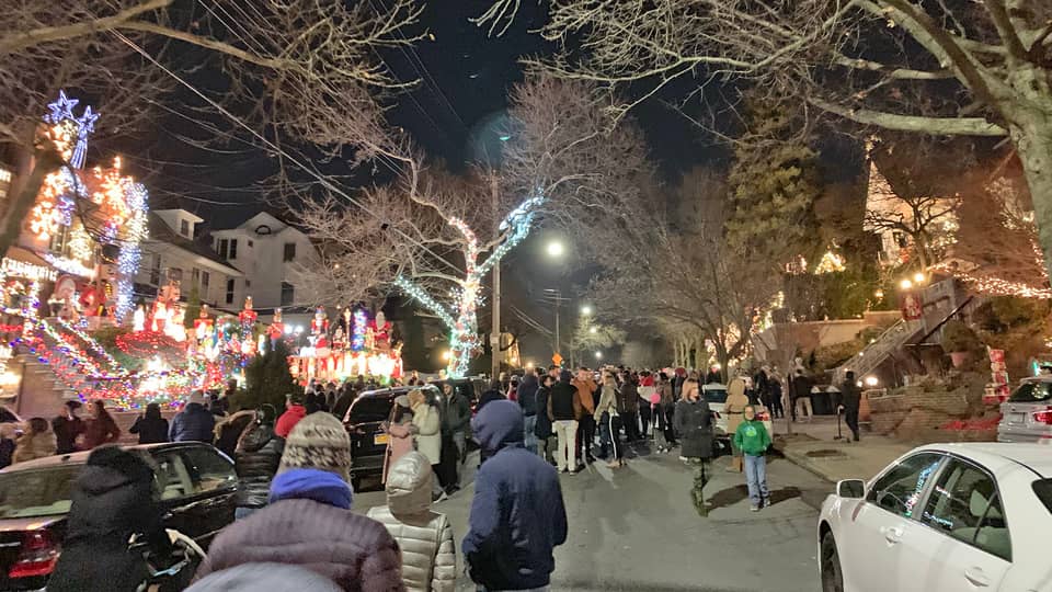 Crowd walking along a street of lit houses