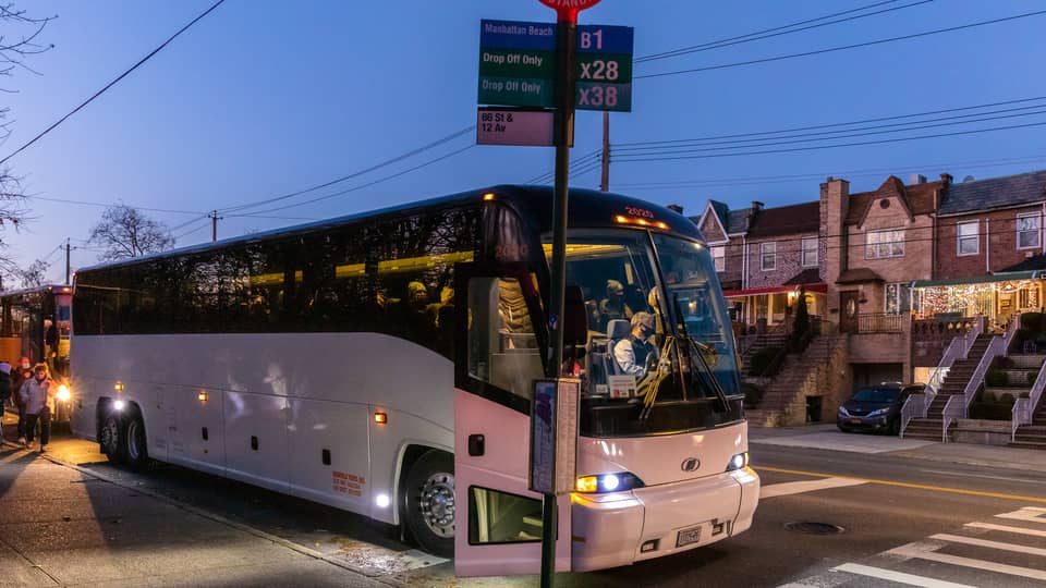 White coach bus stopped on a Brooklyn street at dusk