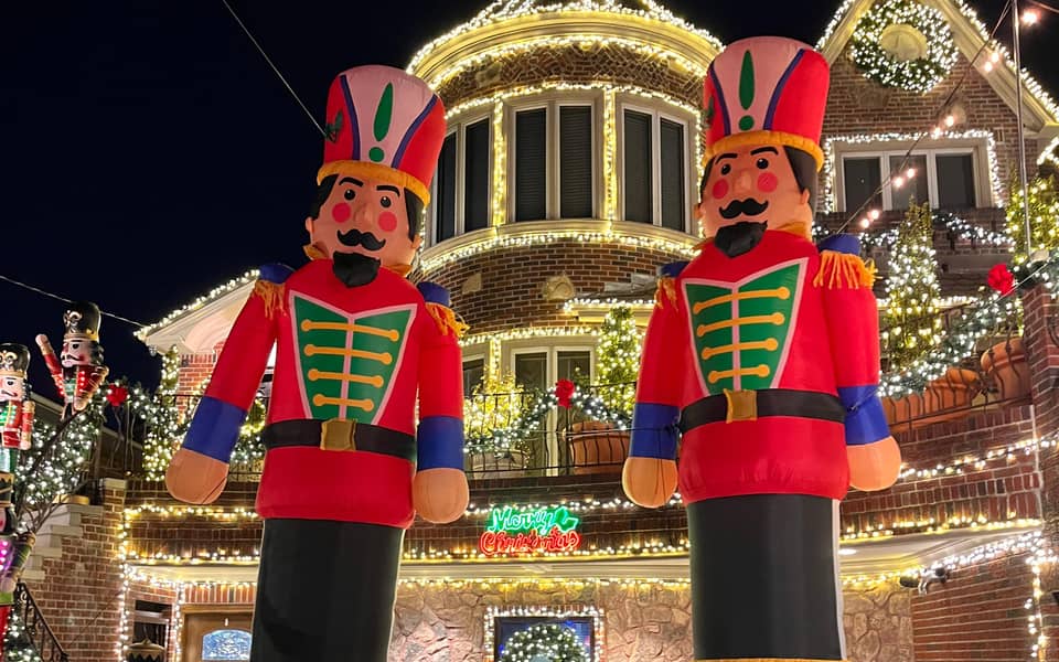 Two large nutcracker figures in front of a lit house
