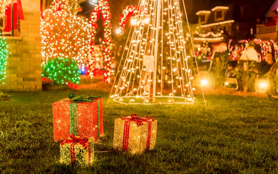 Gift boxes and a light-wrapped tree on a lawn