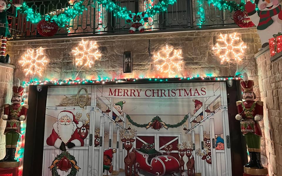 House with wreaths, snowflake lights and a Merry Christmas sign