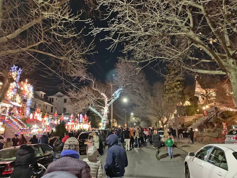 Crowd walking along a street of lit houses