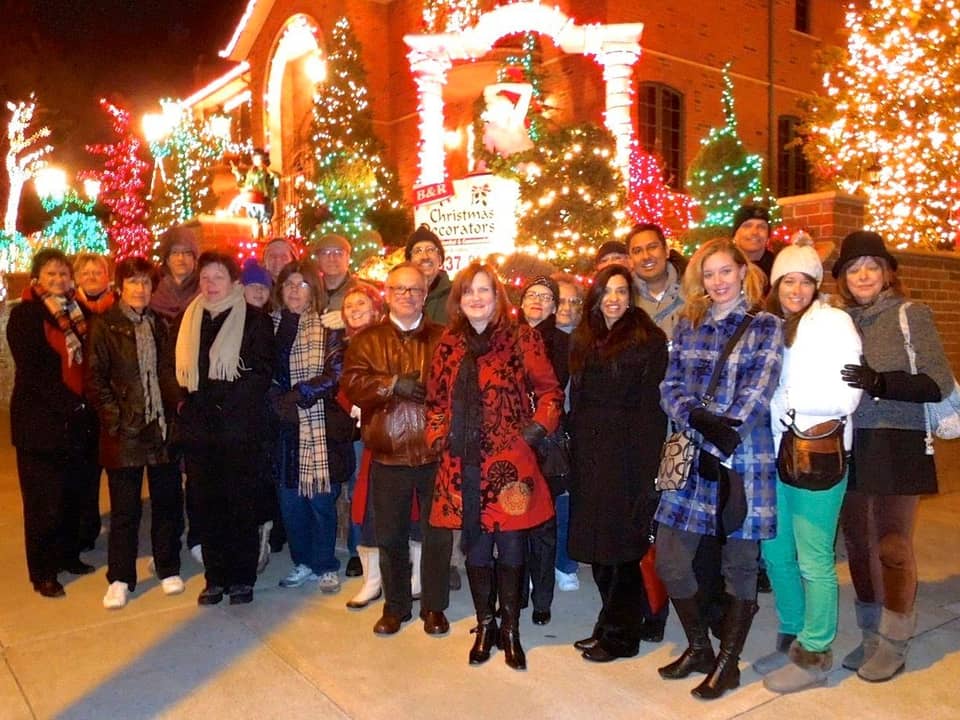 Tour group posing in front of a lit house