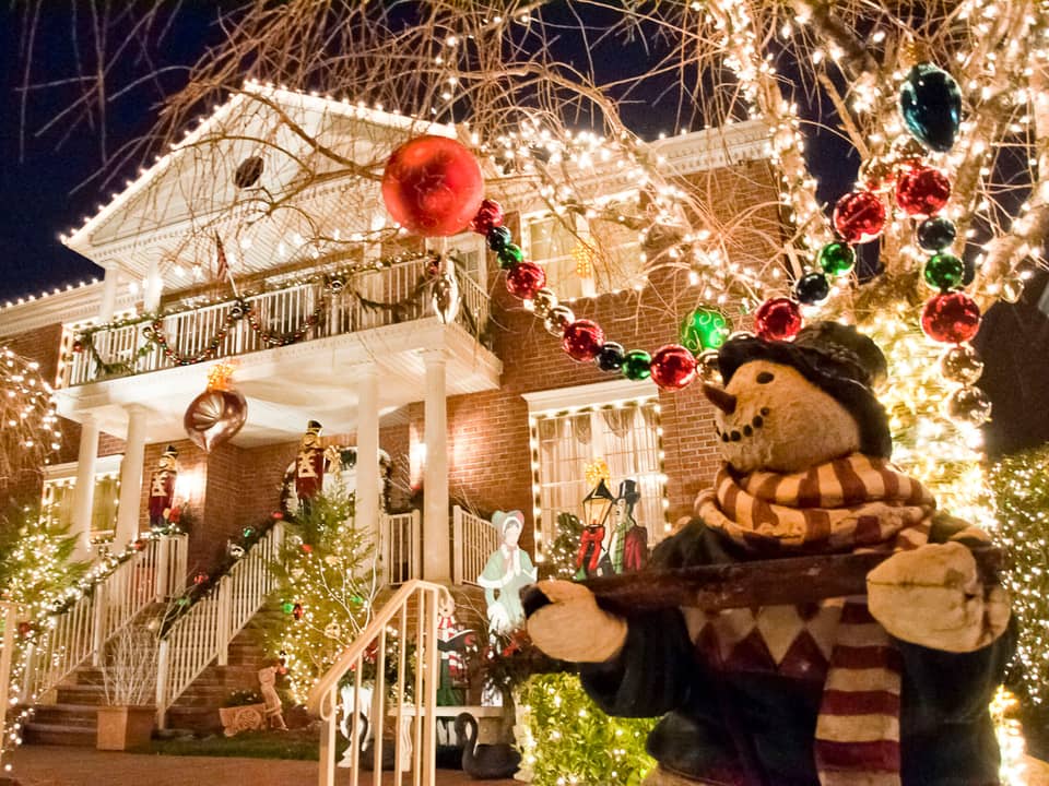 House with a snowman figure and strings of lights