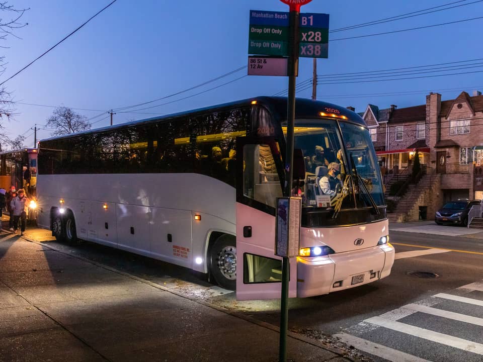 White coach bus stopped on a Brooklyn street at dusk