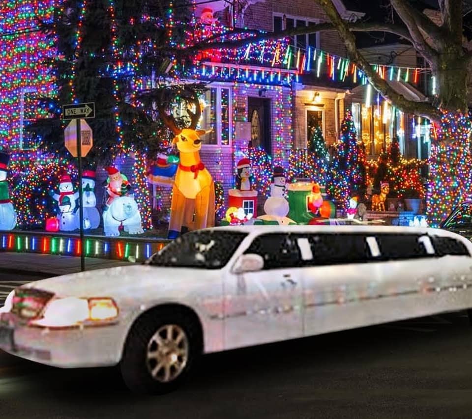 White stretch limousine passing a brightly lit decorated house