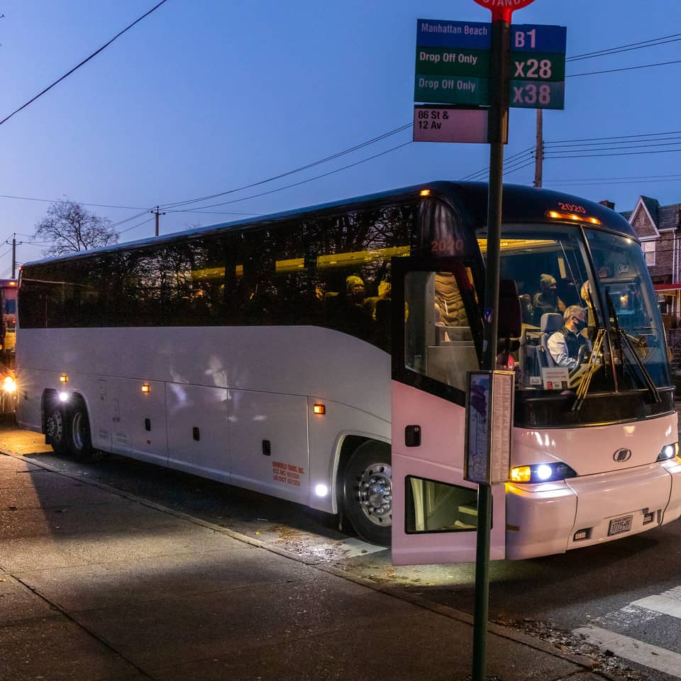 White coach bus stopped on a Brooklyn street at dusk