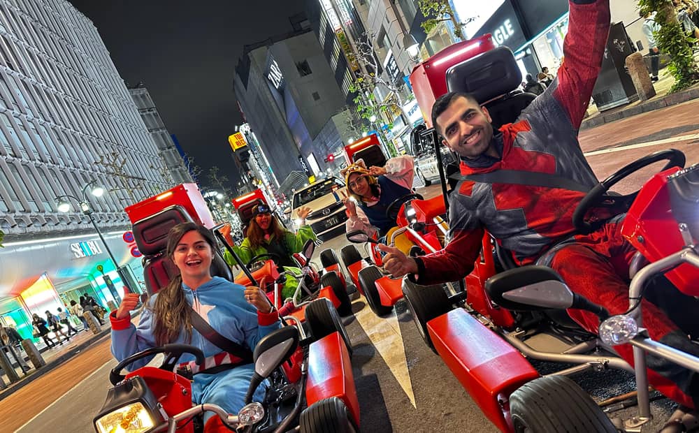 Two drivers in costumes at night on a neon Shibuya street