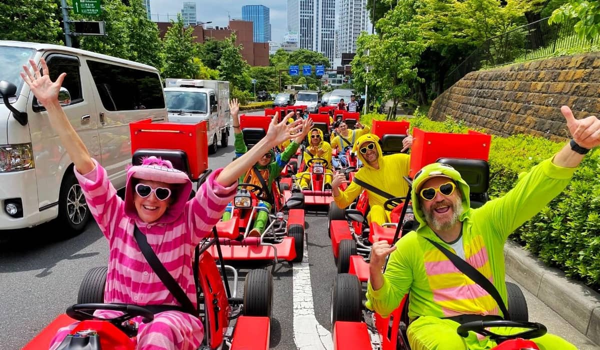 A group in striped onesies in red karts, arms up, on the road. Photo from the operator's GetYourGuide listing.