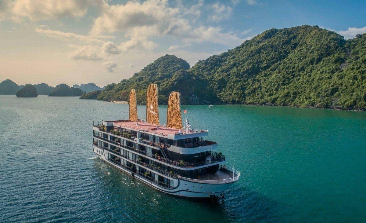 Weißes Kreuzfahrtschiff mit drei Decks zwischen grünen Inseln, von oben gesehen
