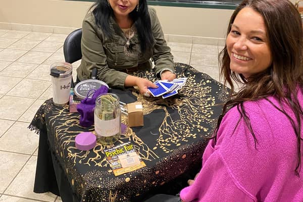 Two people at a table laid with tarot cards and candles