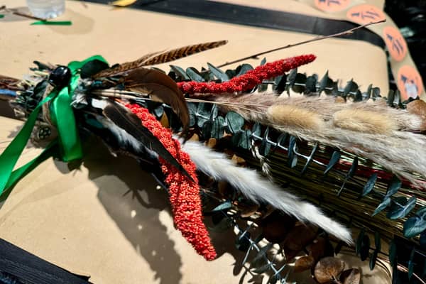 Brooms in progress on a table of ribbon, feathers and twine