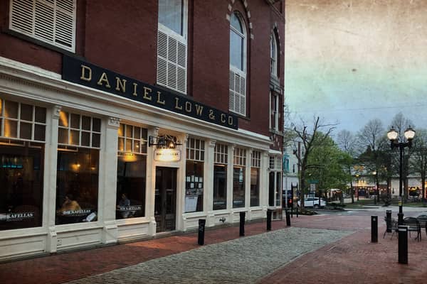 A brick street at dusk with lit shopfronts