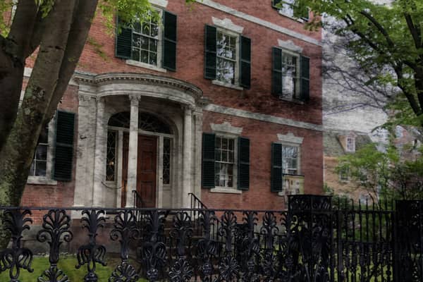A red-brick Federal mansion behind black iron railings