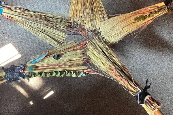 A finished besom laid out with beads and feathers