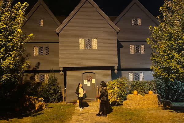 The Witch House at dusk with figures in black on the lawn