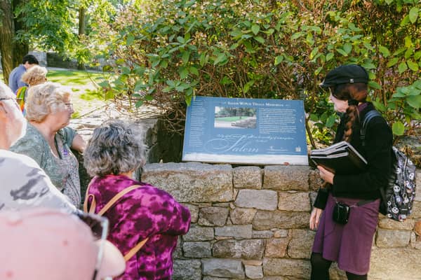 A group listening to a guide read beside an information panel