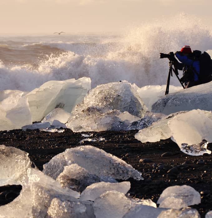 Photographer among ice chunks on black sand