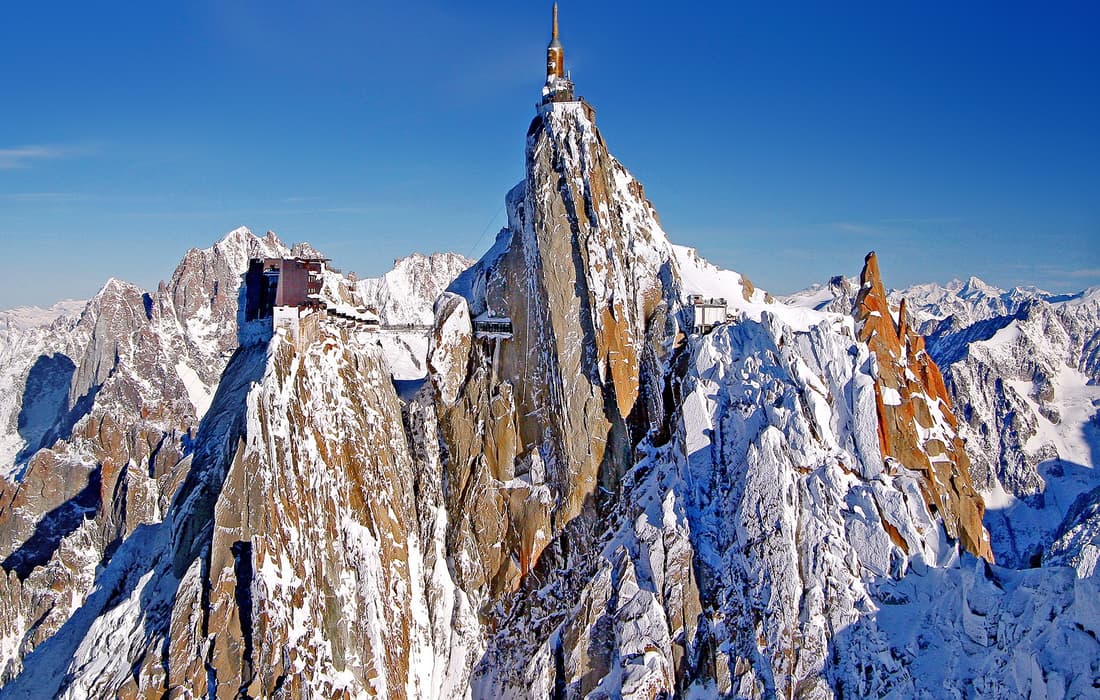 Aiguille du Midi: estación sobre la roca, antena, crestas afiladas gris rojizo en la nieve, desde un mirador alto
