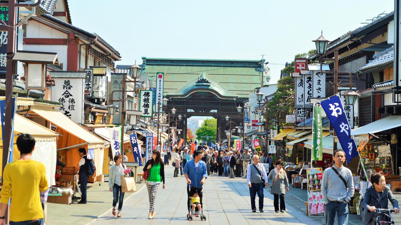 The shop-lined approach to Zenkō-ji, banners along both sides and the temple gate at the far end of the street