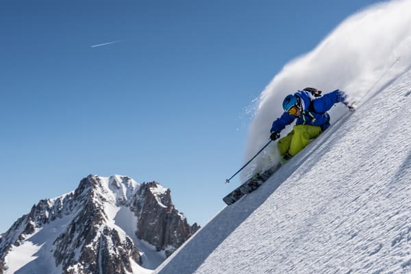 Esquiador de freeride de azul saltando en nieve polvo