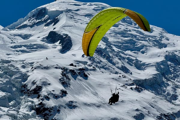 Parapente amarillo verdoso sobre una cresta nevada