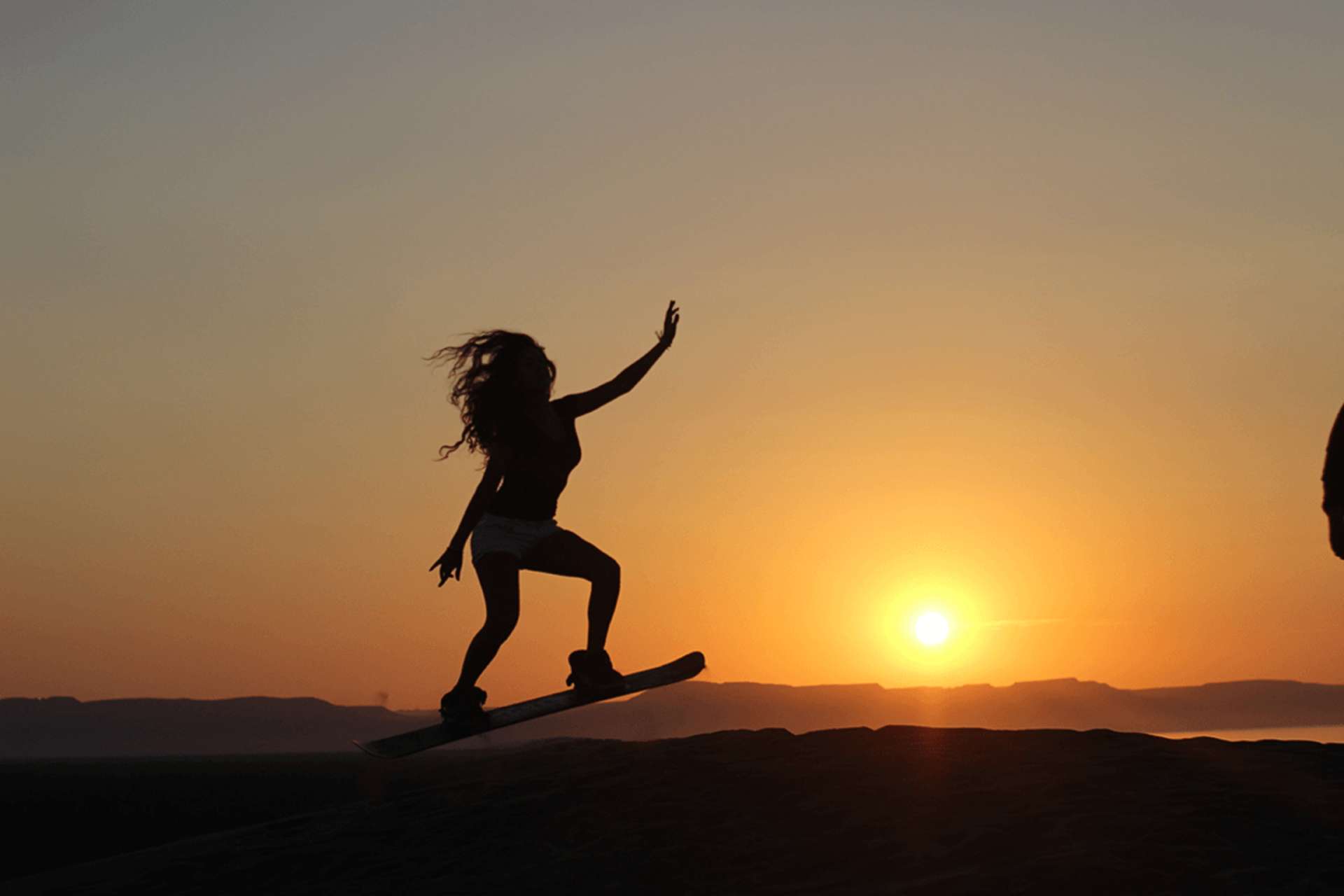 Sandboarding on dunes near Agadir at sunset