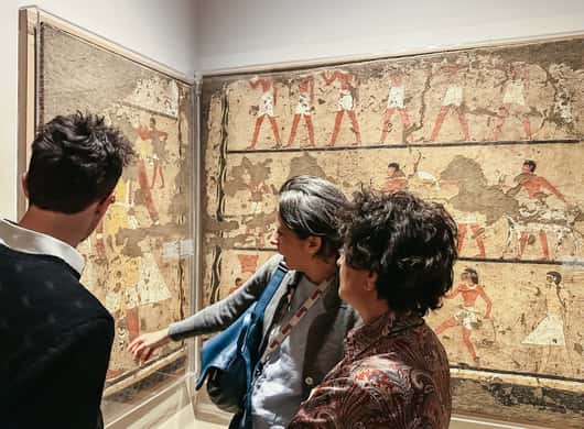 Bezoekers bekijken vitrines met Egyptische objecten in Turijn