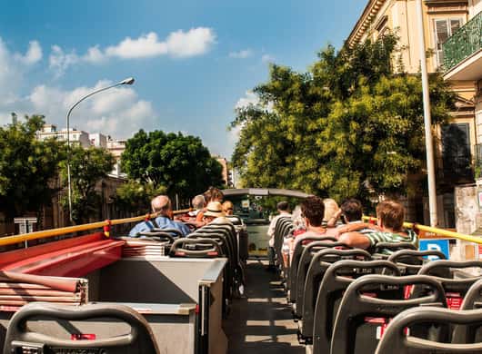 Sightseeingbus bij een historisch gebouw in Palermo