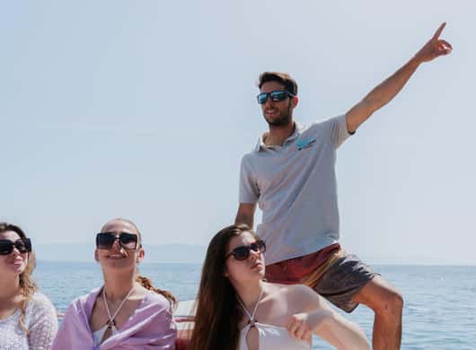 Deelnemers die ontspannen aan boord met uitzicht op de kust bij Cagliari