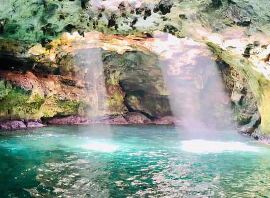 Boot in helderblauw water bij de grotten van Polignano a Mare