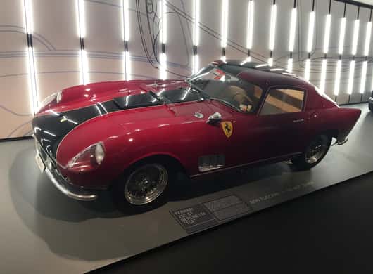 Bezoekers die een collectie supersportwagens bekijken in een museum