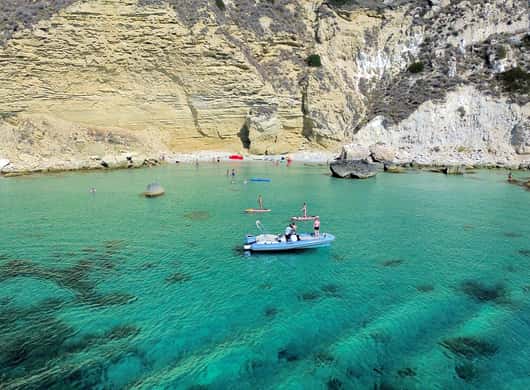 Deelnemers die van de boot springen in het water tijdens een tour bij Cagliari